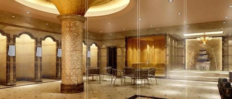A spacious lobby with a large central column, a chandelier, and a reflective floor.
