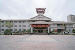 A building with a prominent entrance, a large sign above the entrance, and a parking lot in front.
