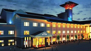 A modern hotel with a prominent tower and a spacious courtyard. - Western Regions Spring Hotel (Wensu)