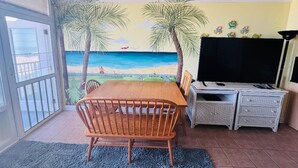 Een eethoek met een houten tafel, stoelen en een televisie op een witte kast.