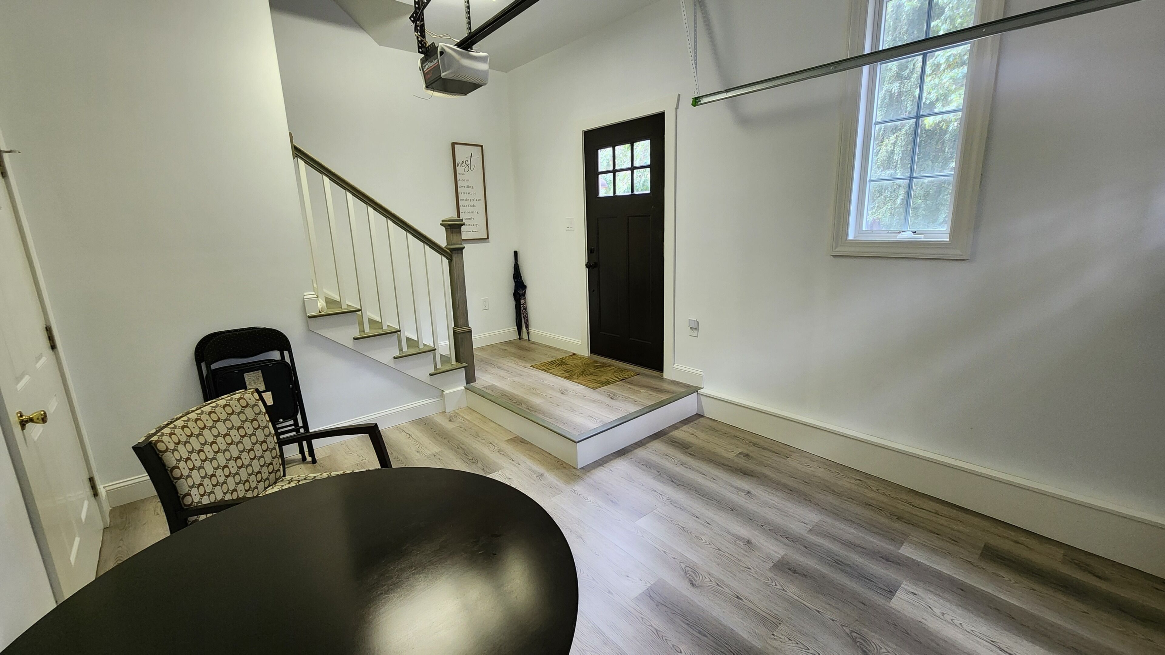 Une pièce spacieuse avec un escalier, une table noire et une chaise à motifs.