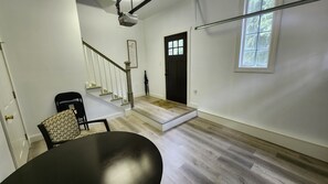 A spacious room with a staircase, a black table, and a patterned chair. - "The Nest" is a unique hideaway in the woods with convenient access. (Titusville)