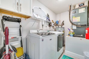 Laundry room with a front-loading washer and dryer, metal shelving, and a laundry basket.