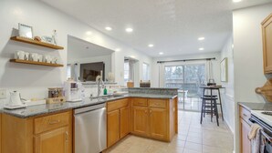 A modern kitchen with wooden cabinets, a granite countertop, and a dishwasher. - Savannah Haven w/ Gazebo, Grill & Fire Pit (Savannah)