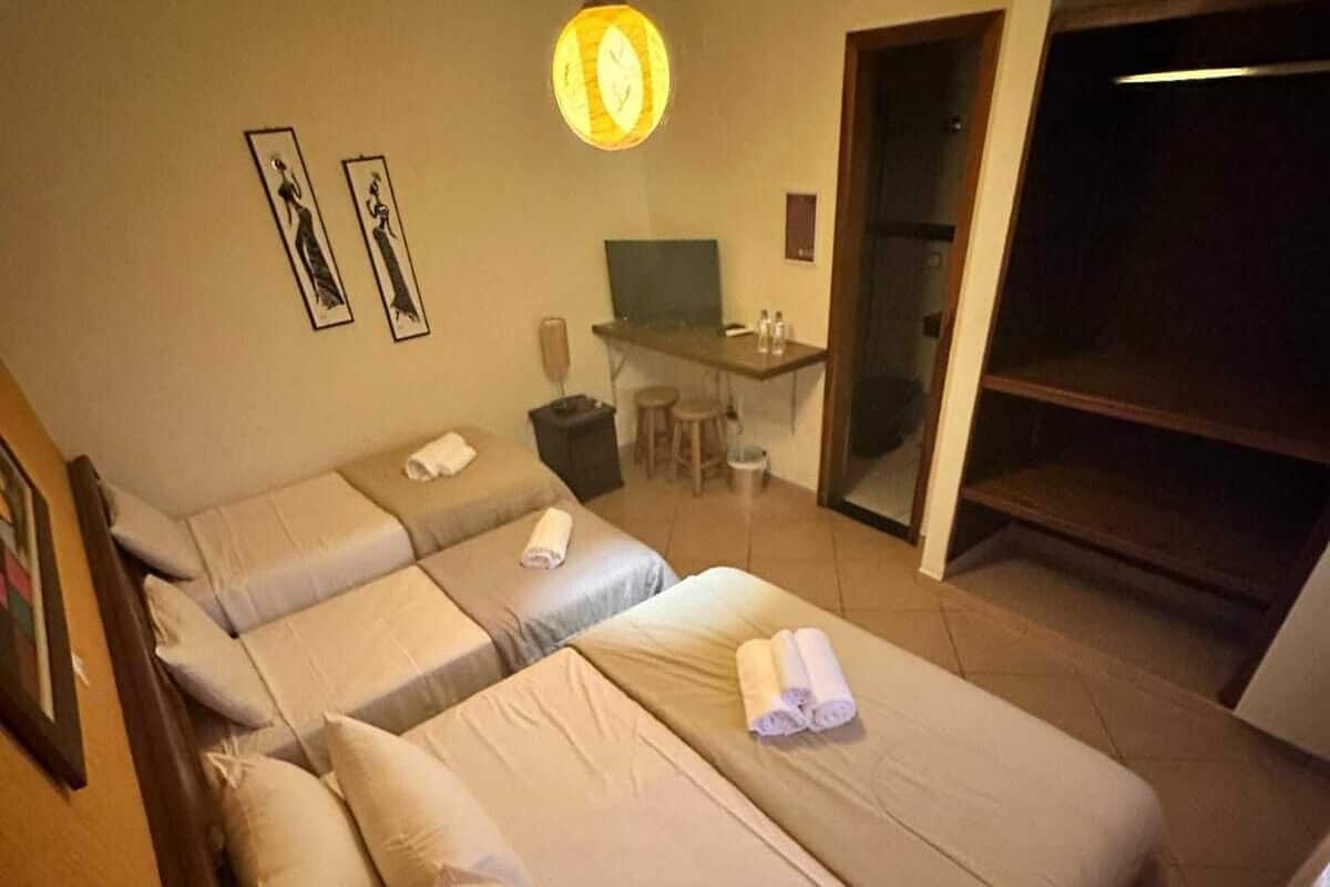 A hotel room with two beds, a desk, a chair, and a television.