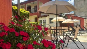 An outdoor patio with stone flooring, beige umbrellas, and metal chairs. - Pousada Villa Zen (Pirenópolis)