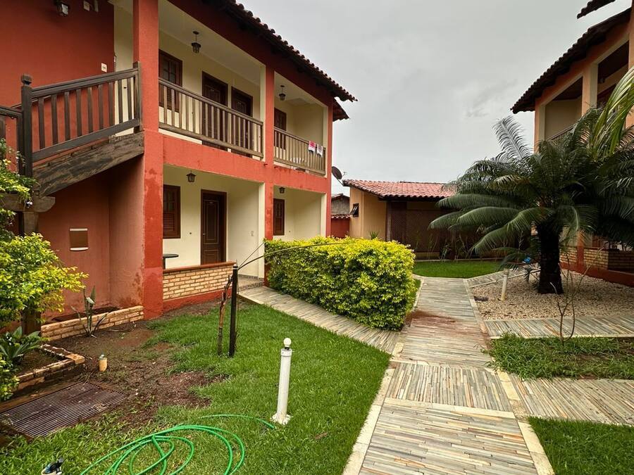 A courtyard with a wooden pathway, a small garden, and a two-story building with balconies.