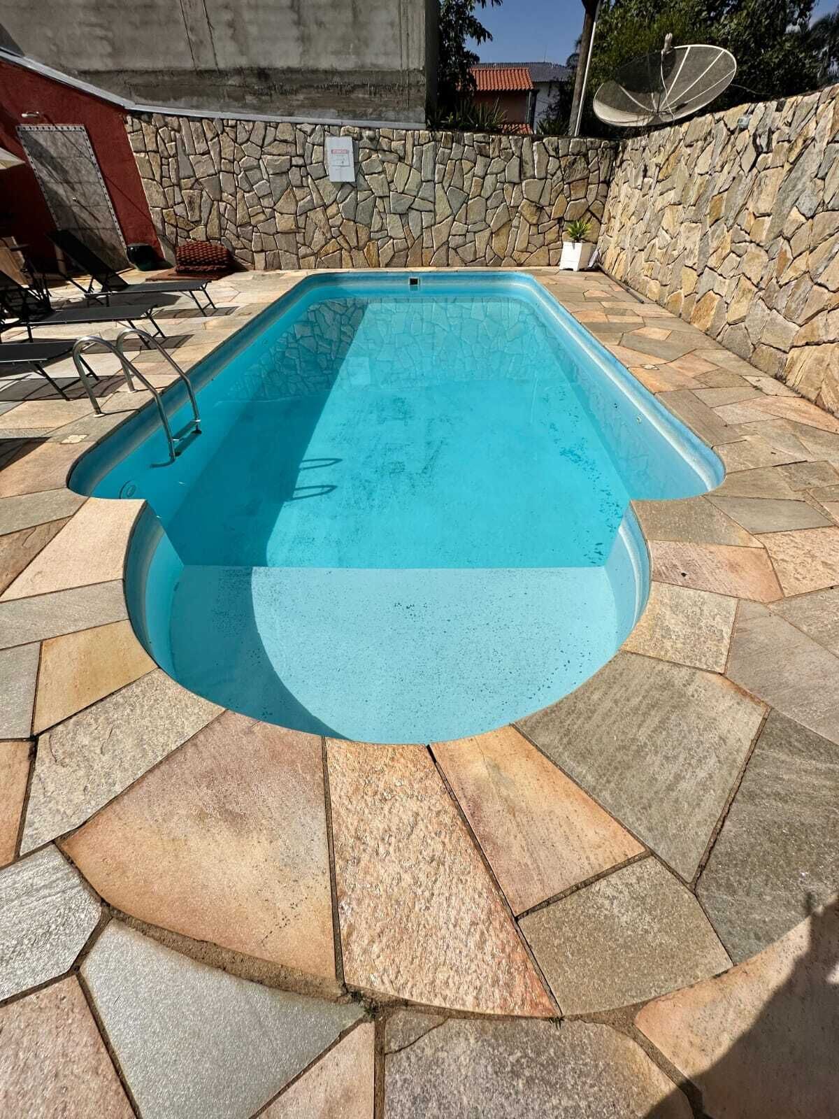 A rectangular swimming pool with a stone wall and tiled deck.