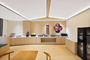 A modern kitchen with a central island, built-in appliances, and a dining area with a wooden table and chairs. - Mizuan Hotel (Jinjiang International Airport) (Jinjiang)