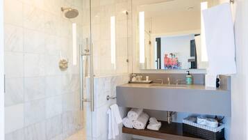 Un baño moderno con ducha envuelta en vidrio, tocador con lavabo y espejo.