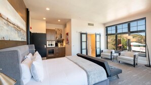 A modern hotel room with a large bed, a kitchenette, a seating area with a table and chairs, and a large window offering a view of the outside. - Lespri by Park City Vacations (Park City)