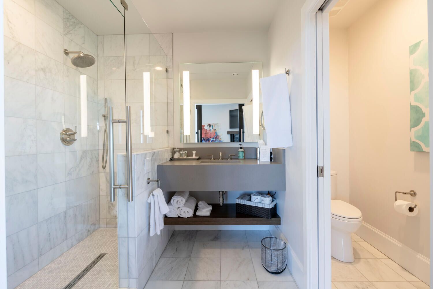 Een moderne badkamer met een douchecabine van glas, een wastafel met spiegel en een toilet.