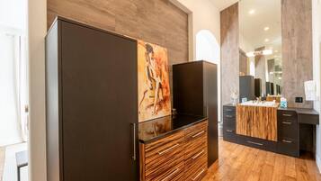A modern bathroom with a wooden vanity, a large mirror, and a painting on the wall.