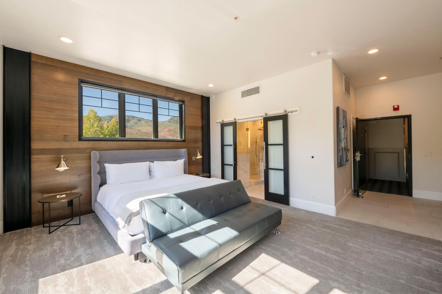 Ein modernes Schlafzimmer mit einem großen Bett, einer Couch, einem Fenster mit Blick und einem begehbaren Kleiderschrank.