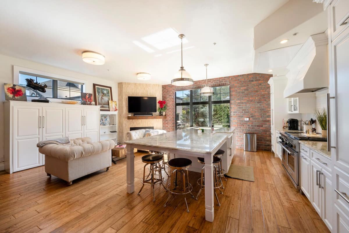 A modern kitchen with a central island, white cabinetry, and a brick accent wall.
