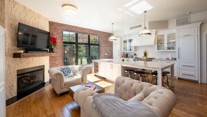A modern living room with a fireplace, a television, and a kitchen with white cabinets and a bar area. - Lespri by Park City Vacations (Park City)