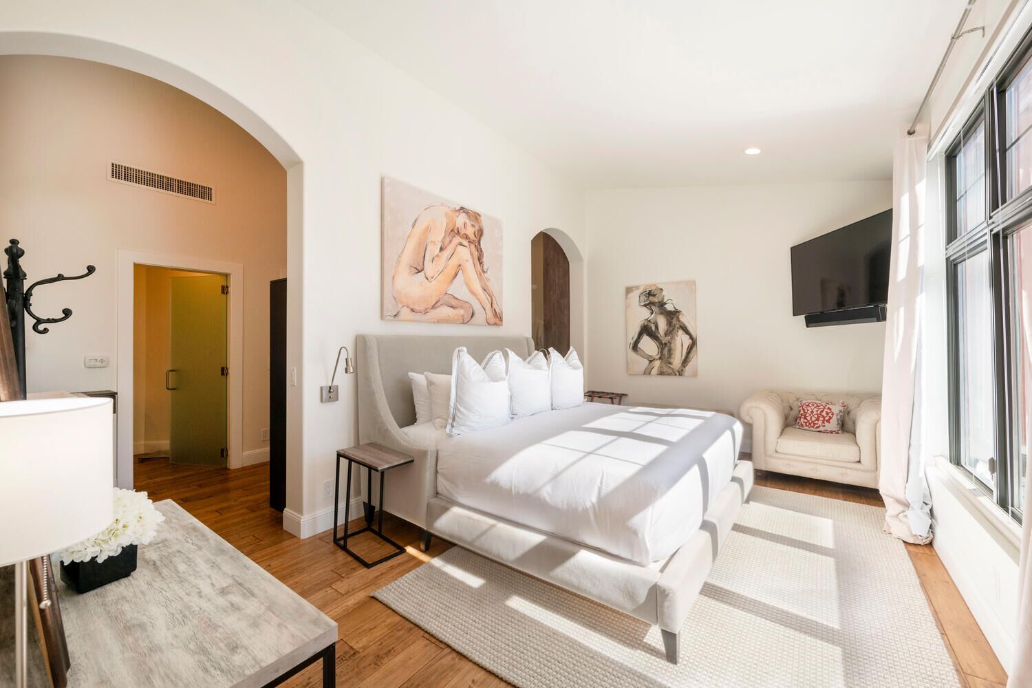 A modern bedroom with a large bed, a sofa, a TV, and artwork on the walls.