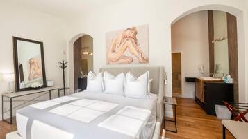Um quarto moderno com uma cama grande, uma toucador com espelho e um quadro na parede.