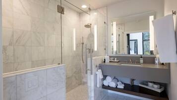 A modern bathroom with a glass-enclosed shower, a large mirror, and a vanity with a sink and towel rack.