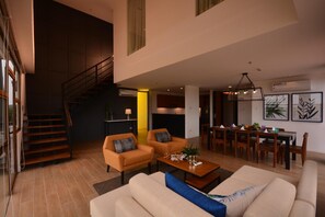 A spacious living area with a staircase, a dining area, and a kitchen. - Crown Hotel Palawan at Harbour Springs (Puerto Princesa)