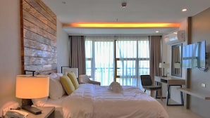 A hotel room with a large bed, a desk, a chair, a TV, and a phone on the nightstand. - Crown Hotel Palawan at Harbour Springs (Puerto Princesa)