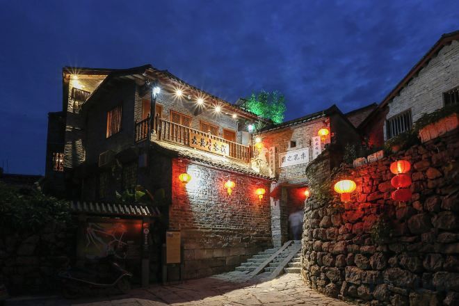 A traditional building with a stone facade, a wooden balcony, and a staircase leading to the entrance.