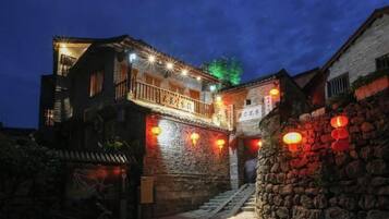 A traditional building with a stone facade, a wooden balcony, and a staircase leading to the entrance.