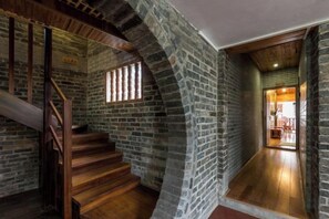 A staircase with wooden steps and a brick wall, leading to a room with a wooden floor and a window. - Huangyao Ancient Town (Zhaoping)