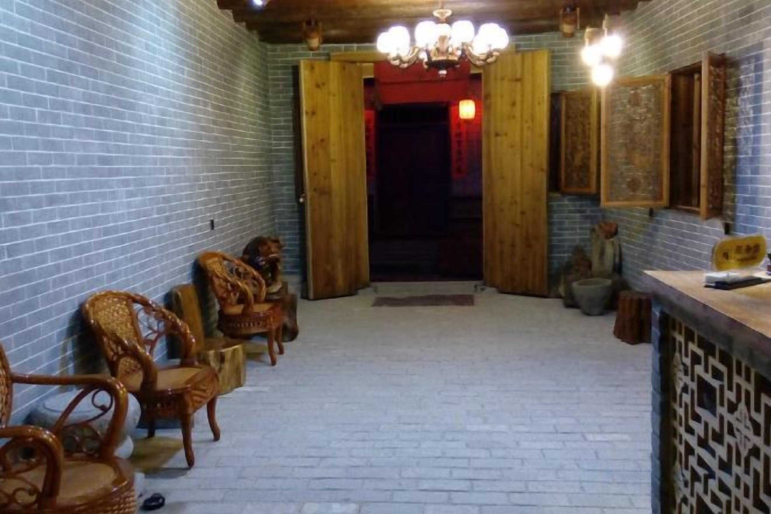 Un pasillo con sillas de madera tradicionales alineadas, una recepción y un papel tapiz estampado.