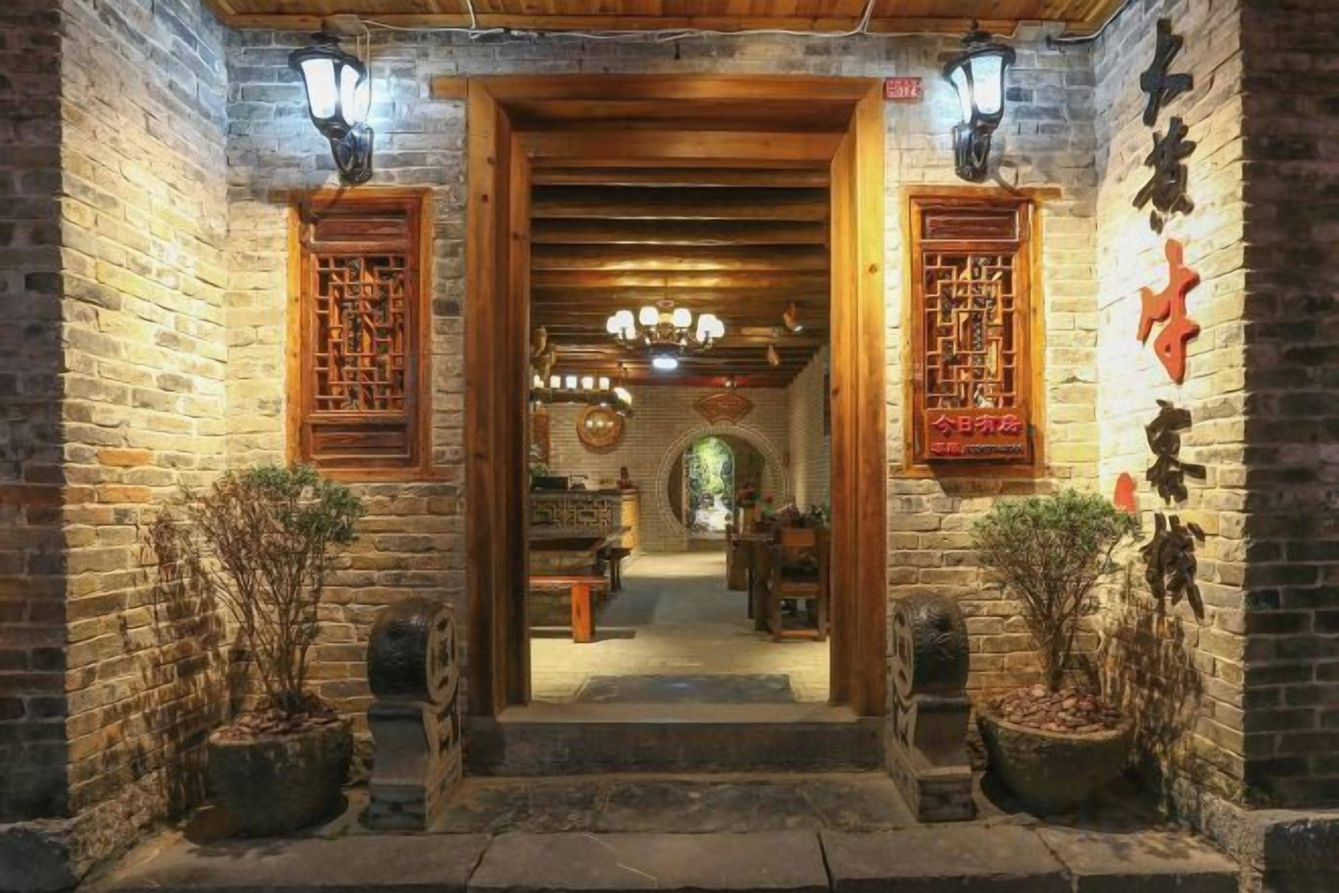 Une cour traditionnelle chinoise, avec des portes en bois, des lanternes et des plantes en pot.