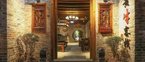 A traditional Chinese courtyard with wooden doors, lanterns, and potted plants.