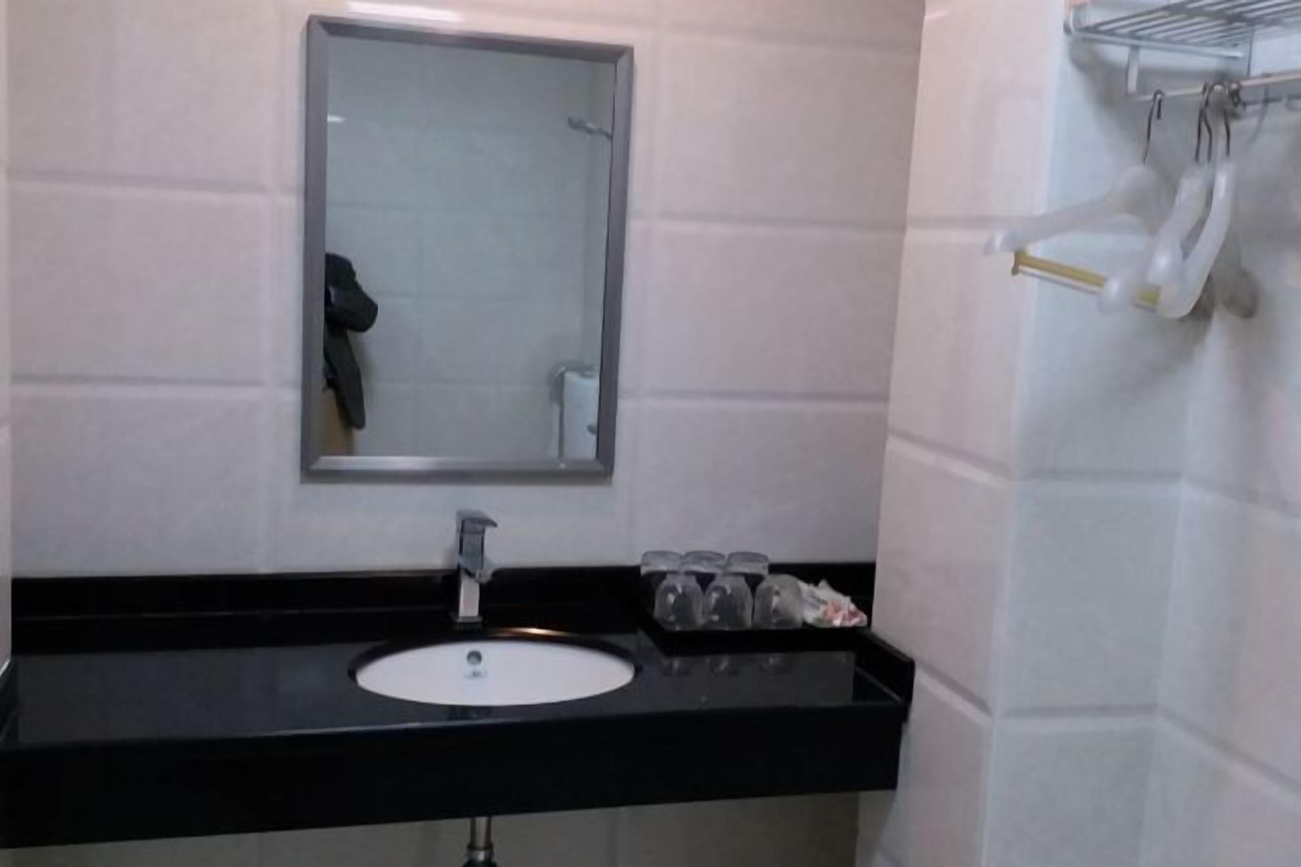 A bathroom with a black countertop, a white sink, a mirror, and a towel rack with towels.