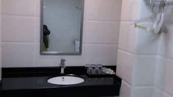A bathroom with a black countertop, a white sink, a mirror, and a towel rack with towels.