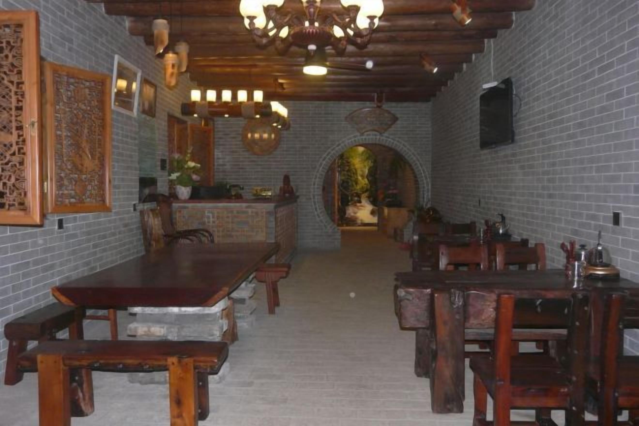 Un comedor tradicional con mesas y sillas de madera, una pared de ladrillo y una araña.