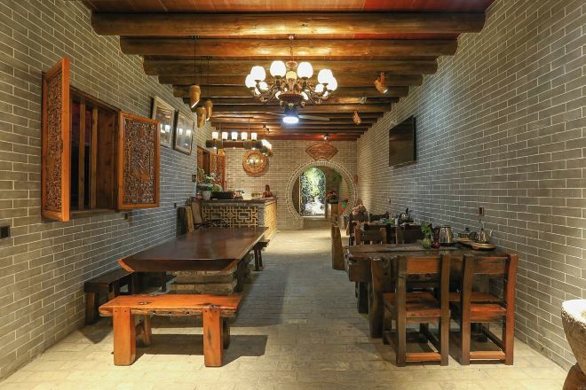 A long dining hall with brick walls, wooden benches, and a central table.