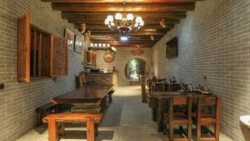 A long dining hall with brick walls, wooden benches, and a central table.