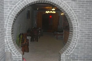 Un pasillo con paredes de ladrillo y una puerta de madera al final.