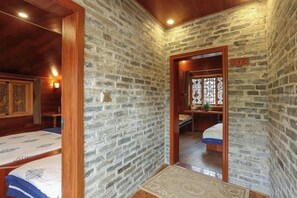 A room with stone walls, a wooden ceiling, and a bed with a patterned bedspread. - Huangyao Ancient Town (Zhaoping)