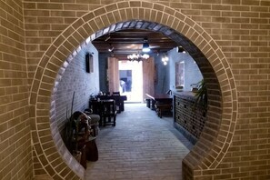 A brick-walled corridor with tables and chairs, leading to a doorway. - Huangyao Ancient Town (Zhaoping)
