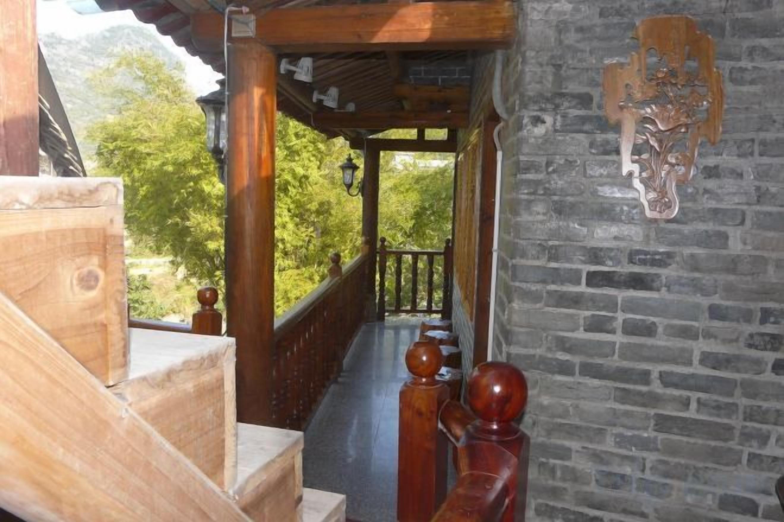 Una escalera de madera que lleva a un balcón con un muro de ladrillo y un cabecero de madera decorativo.