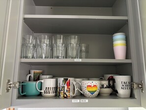 Un mueble con estantes que contiene varias tazas y vasos.