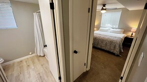 A bedroom with a bed, a nightstand, and a window with blinds.