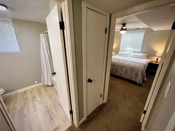 A bedroom with a bed, a nightstand, and a window with blinds.