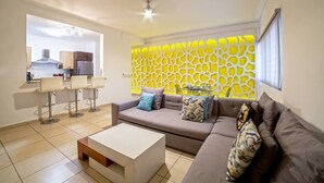 A modern living room with a sofa, coffee table, and bar stools. A kitchen is visible in the background. - - Check-in from 3:00pm.<br>- Check-out before 11:00am.<br>- Smoking is not... (Puerto Vallarta)