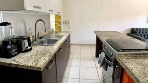 Une cuisine moderne dotée de plans de travail en granit, d’un four encastré, d’un évier et d’un grille-pain.