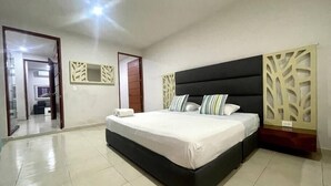 Une chambre à coucher avec un grand lit, une armoire, un miroir et une porte donnant sur une autre pièce.