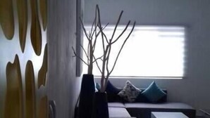 En moderne stue med sofa, sofabord og en dekorativ vase med grene.