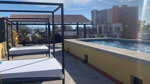 Poolområde på taget med pergola, liggestole og udsigt over bybilledet.