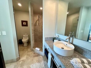 Ein Badezimmer mit einem großen Waschbecken, einer Dusche und einer Toilette.