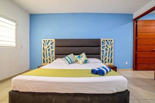 A bedroom with a bed, pillows, a bedside table, and a wooden door. - Perfect for couples! Great location in Versalles! (Puerto Vallarta)